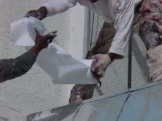 Crew of Roof Menders apply a base coating