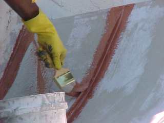 Roof Menders crew chief uses hand brush to apply detail portion of work