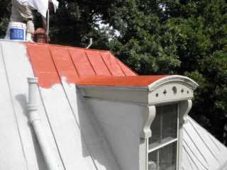 Roof Menders crew applying traditional red top coating with water-based acrylic