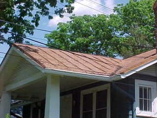 Overhang of trees damaging front panels before process of sealer for tin roof application by crew of Roof Menders